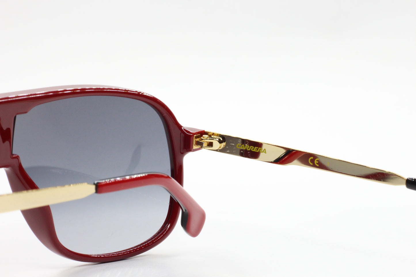 Close-up of aviator style Carrera sunglasses with red frames and gold temples by ABC Optical