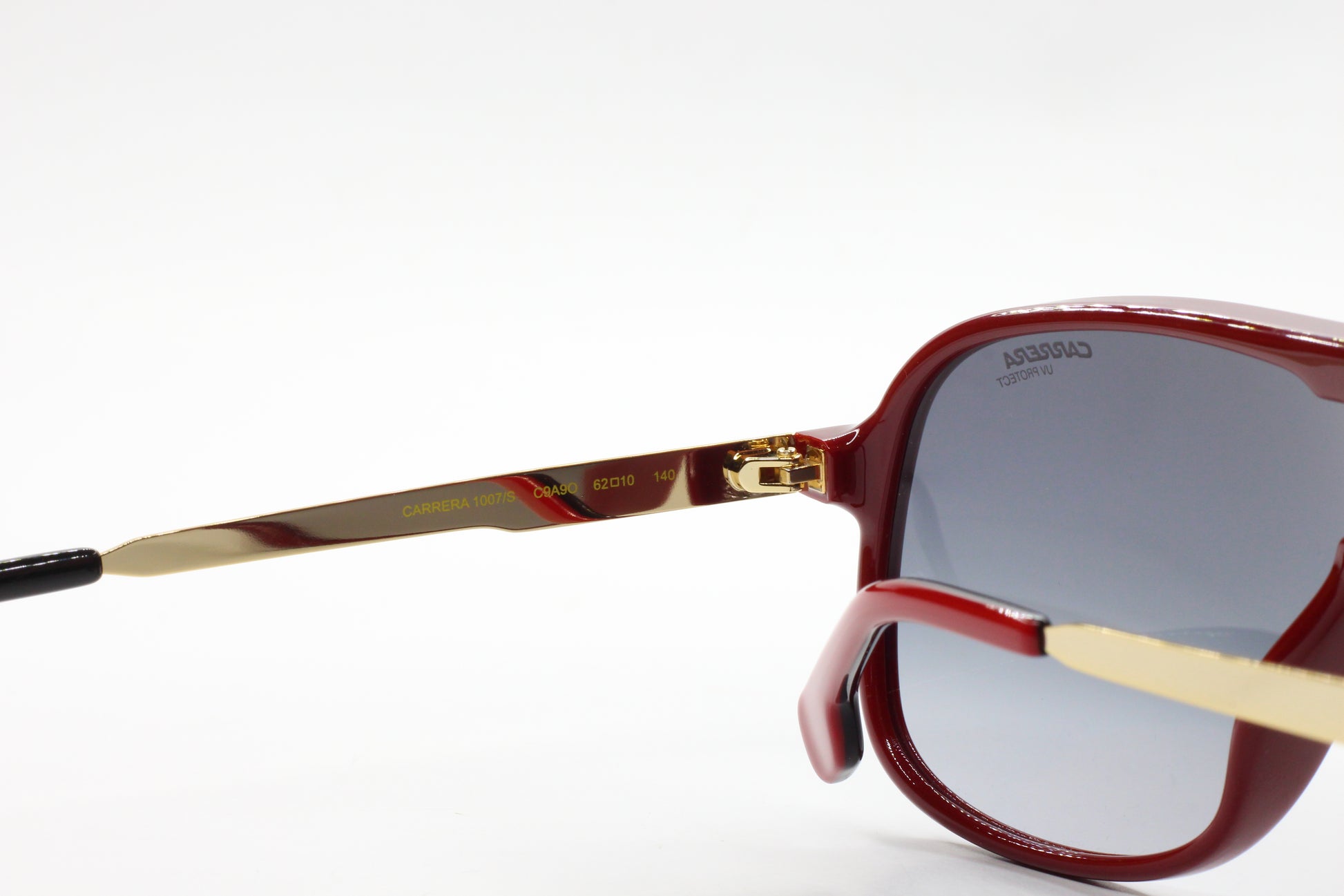 Close-up of aviator style Carrera sunglasses with red frames and gold temples from ABC Optical