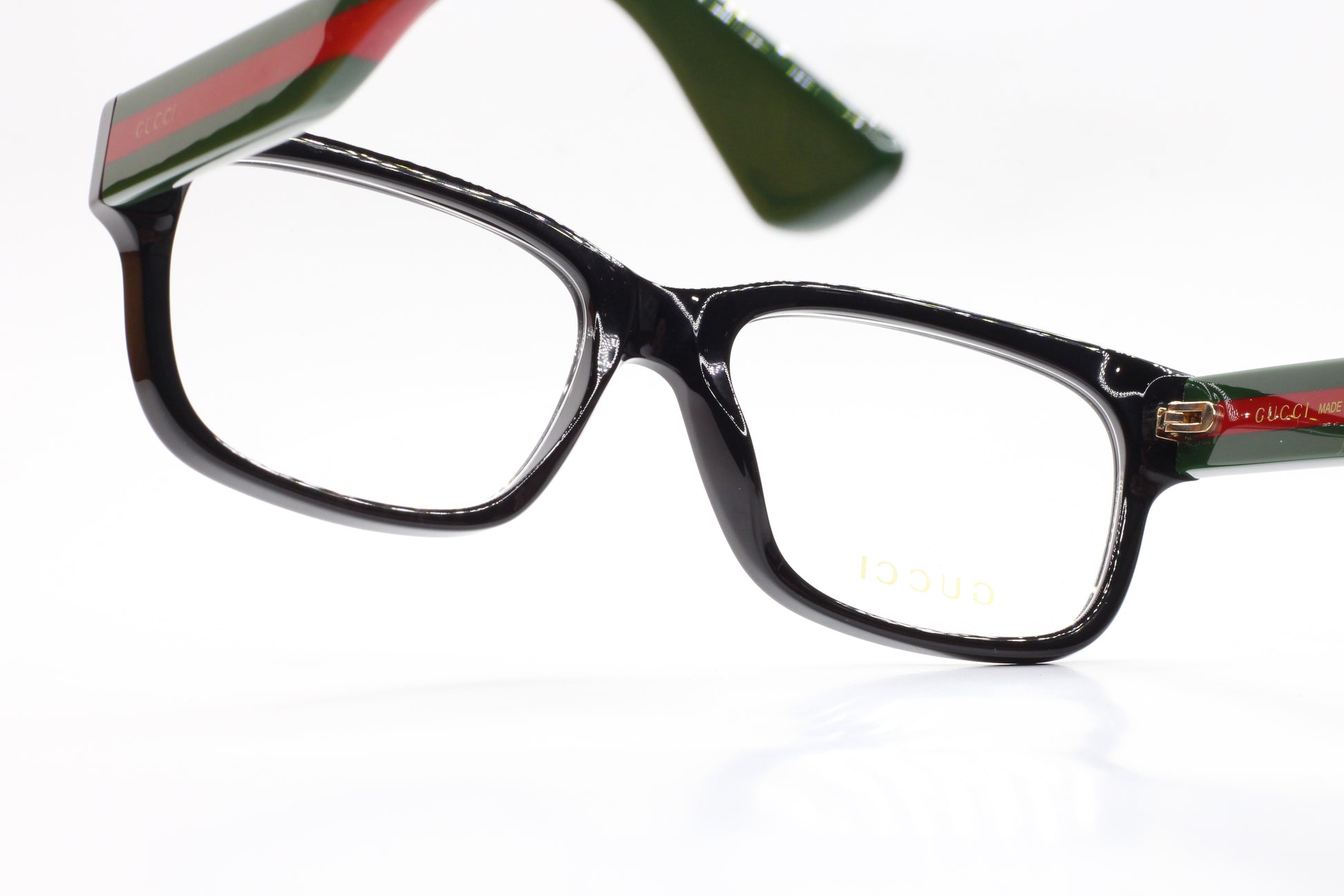Close-up of Gucci GG0343O 007 eyeglasses for sale with black rectangular frames and green red temple stripes